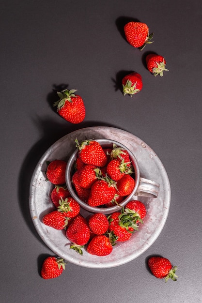 Concetto di cibo estivo con una fragola su uno sfondo di pietra nera. Bacche aromatiche mature, luce dura moderna, ombra scura, vista dall'alto