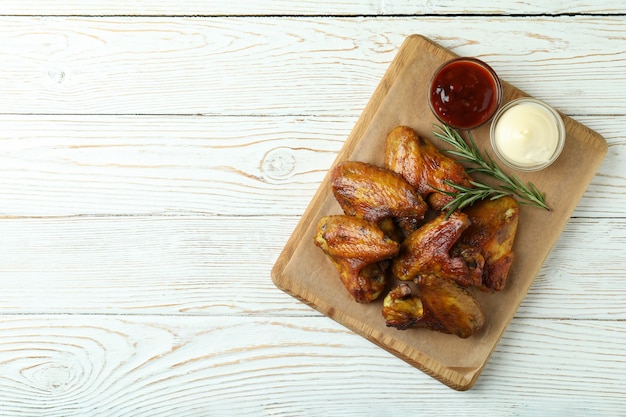 Concetto di cibo gustoso con ali di pollo al forno su legno bianco