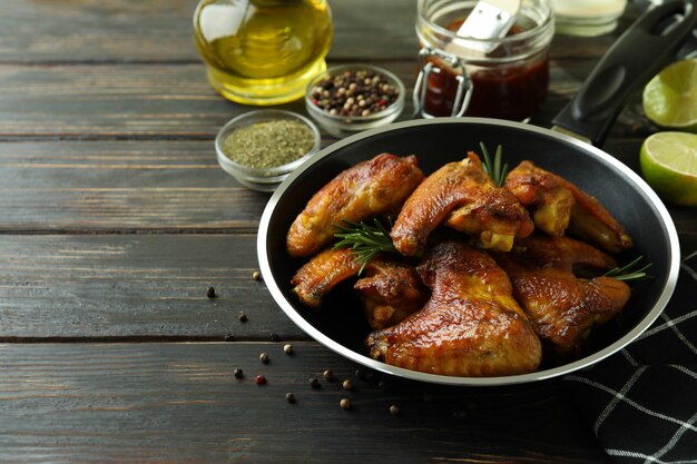 Concetto di cibo gustoso con ali di pollo al forno su sfondo di legno, spazio per il testo