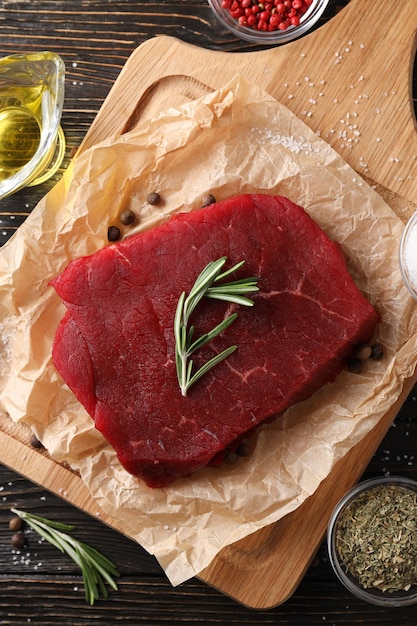 Concetto di cibo gustoso con bistecca di manzo cruda su fondo di legno