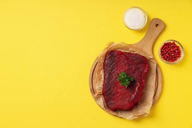 Concetto di cibo gustoso con bistecca di manzo cruda su sfondo giallo