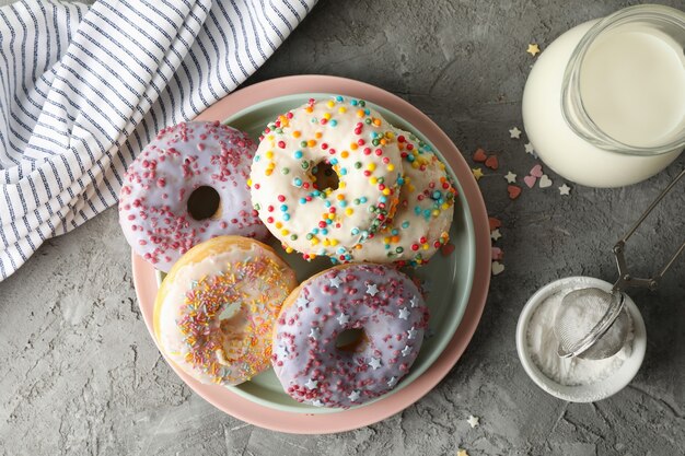 Concetto di cibo gustoso con ciambelle e latte su sfondo grigio