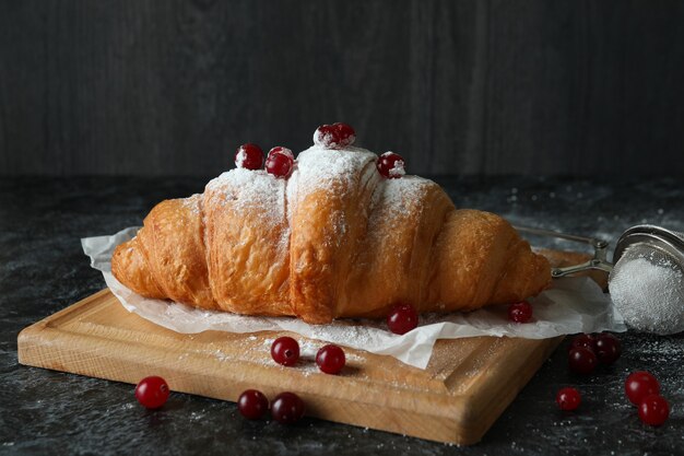 Concetto di cibo gustoso con croissant su oscurità