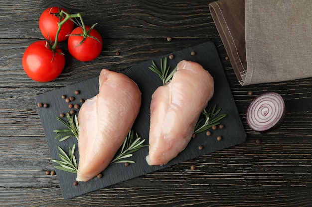 Concetto di cibo gustoso con fette di filetto di pollo crudo su fondo di legno