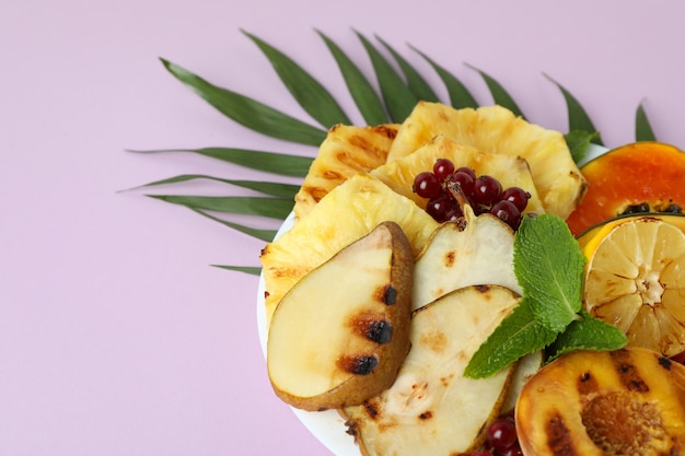 Concetto di cibo gustoso con frutta alla griglia su sfondo viola.