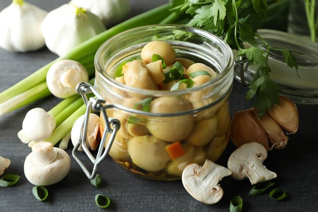 Concetto di cibo gustoso con funghi marinati su tavola di legno scuro