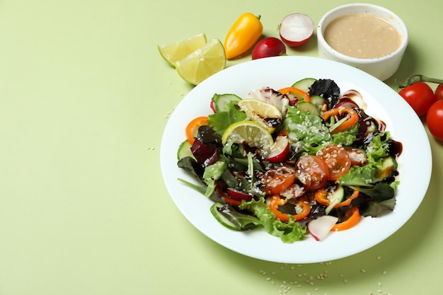 Concetto di cibo gustoso con insalata di verdure con salsa tahini su sfondo verde