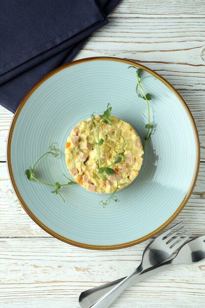 Concetto di cibo gustoso con insalata Olivier su tavolo di legno bianco