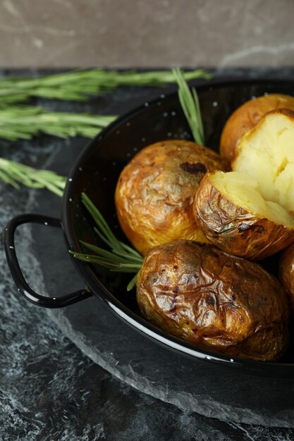 Concetto di cibo gustoso con patate al forno sul tavolo affumicato nero.