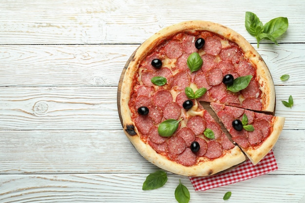 Concetto di cibo gustoso con pizza al salame su fondo di legno bianco