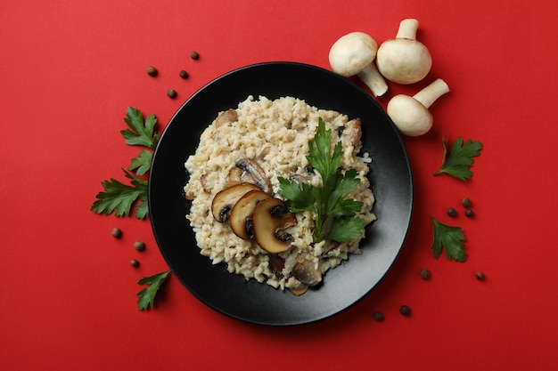 Concetto di cibo gustoso con risotto ai funghi su sfondo rosso