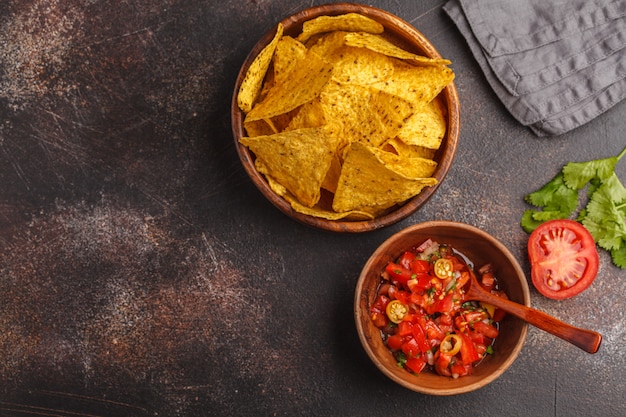 Concetto di cibo messicano. Nachos - mais giallo totopos chips con salsa di pomodoro pico del gallo, vista dall&#39;alto, copia spazio.