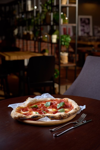 Concetto di cibo. Pizza italiana originale fresca su una tavola di legno in pizzeria o ristorante italiano.