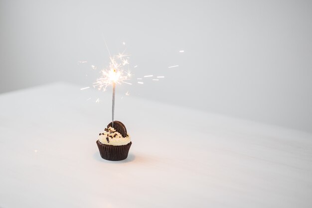 Concetto di cibo, prodotti da forno, vacanze, buon compleanno e dessert - delizioso cupcake con sparkler e