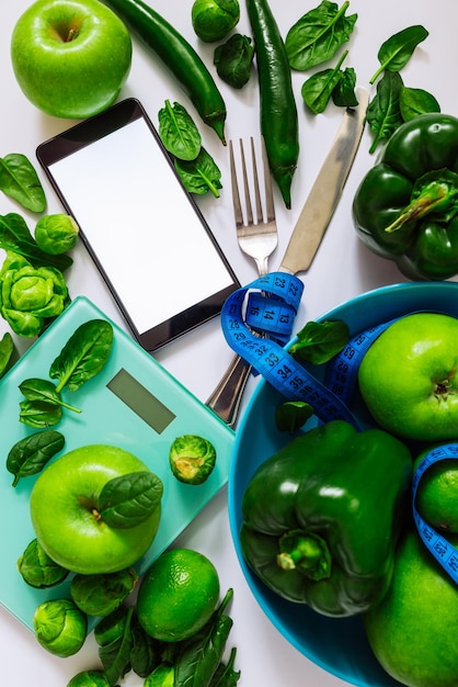 Concetto di cibo sano. cibo verde su sfondo bianco. telefono cellulare con schermo bianco.