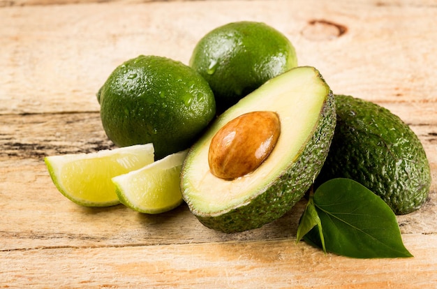 concetto di cibo sano - fette di avocado e lime su sfondo di legno
