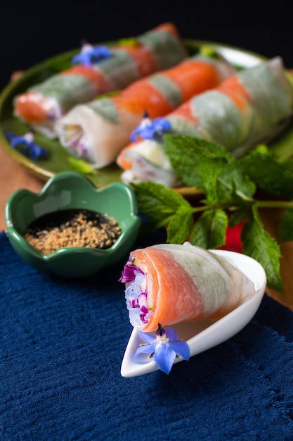 Concetto di cibo sano Involtini primavera di carta di riso al salmone affumicato fresco con verdure colorate con spazio di copia