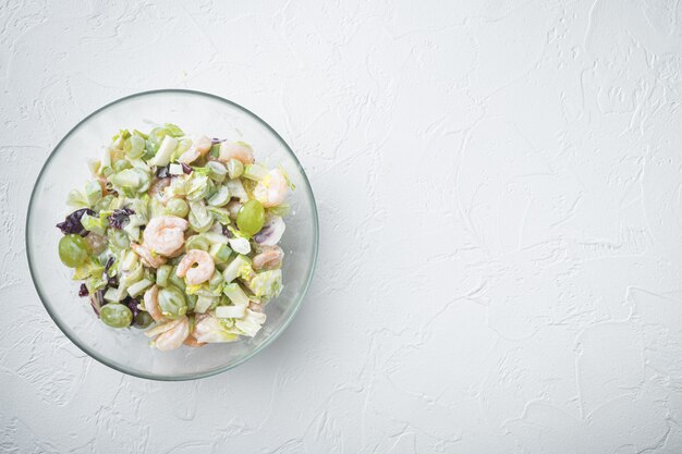 Concetto di cibo sano, piatto di insalata dietetica. Insalata di pesce fresco con gamberi o set di gamberetti, con salsa di mele e uva, sul tavolo bianco, vista dall'alto laici piatta