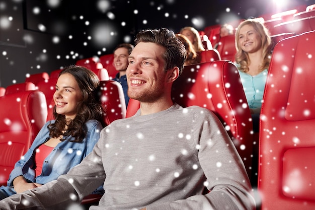 concetto di cinema, intrattenimento e persone - amici felici che guardano film a teatro con i fiocchi di neve