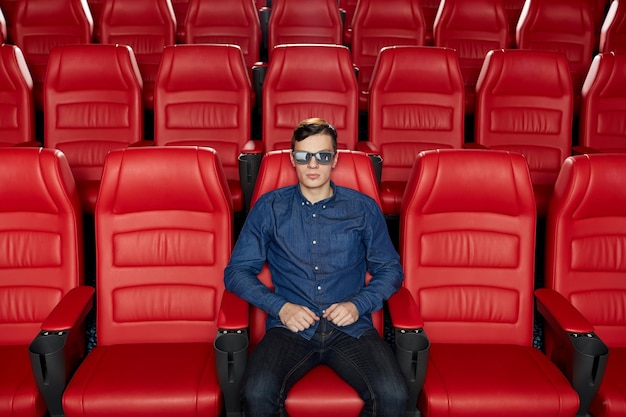 concetto di cinema, tecnologia, intrattenimento e persone - giovane con occhiali 3d che guarda film da solo nell'auditorium vuoto del teatro