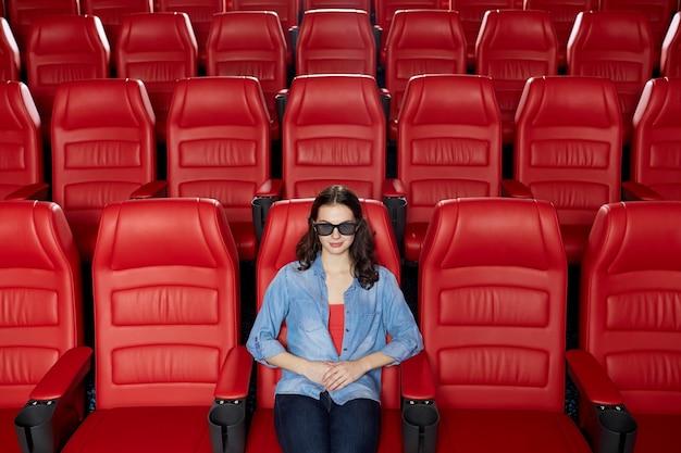 concetto di cinema, tecnologia, intrattenimento e persone - giovane donna con occhiali 3d che guarda film da sola nell'auditorium vuoto del teatro