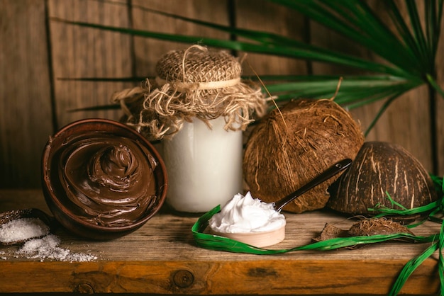 Concetto di cioccolato e cocco Spa su uno sfondo di legno Trattamento della pelle del corpo al cioccolato Ciotola di cioccolato fuso e olio di cocco