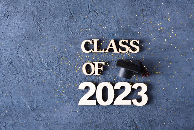 Concetto di classe 2023 Numero in legno 2023 con tappo graduato su fondo in cemento scuro con tinsel