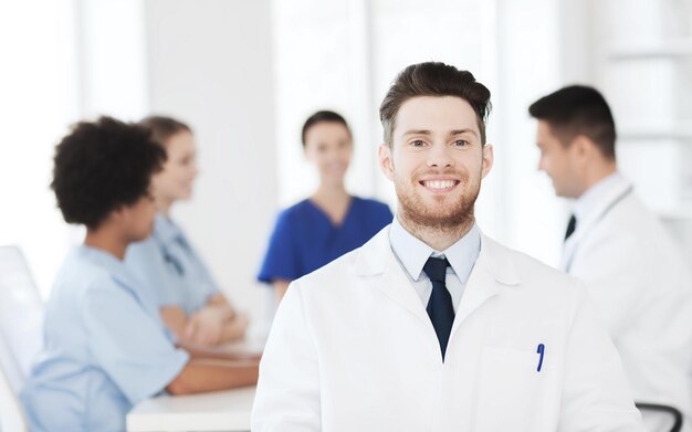 concetto di clinica, professione, persone e medicina - medico maschio felice su un gruppo di medici che si incontrano in ospedale