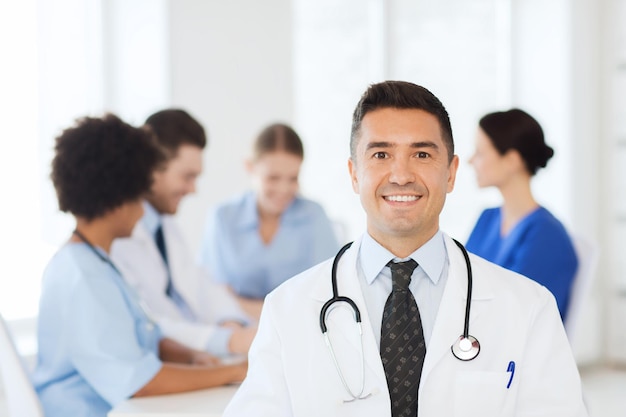 concetto di clinica, professione, persone e medicina - medico maschio felice su un gruppo di medici che si incontrano in ospedale