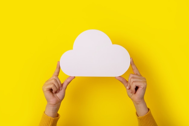 Concetto di cloud computing, mani che tengono il cloud su sfondo giallo, cloud storage