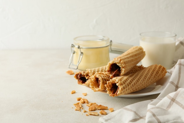 Concetto di colazione con rotoli di wafer con latte condensato su bianco strutturato