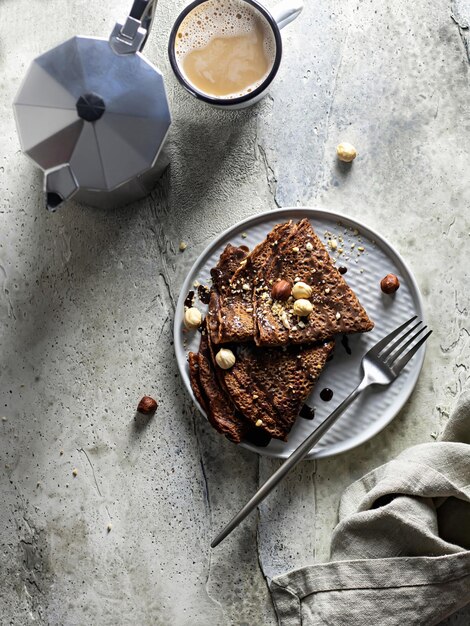 Concetto di colazione Crepes al cioccolato con noci e salsa di cioccolato su uno sfondo strutturato vista dall'alto