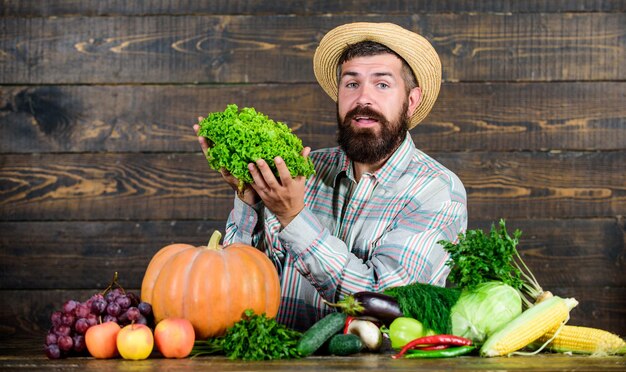 Concetto di colture coltivate localmente. Acquista verdure dell'azienda agricola locale. Tipico contadino. Festa del raccolto del mercato agricolo. L'uomo maturo agricoltore barbuto tiene il fondo di legno delle verdure. Vendi verdura. Mercato locale.