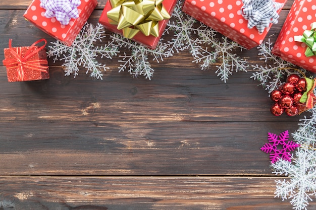Concetto di condimento di Natale, Capodanno e festività. Molti confezione regalo rosso con bel nastro, fiocco di neve e molti tipi di ornamenti su tavola di legno con spazio di copia.