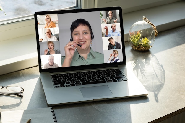 Concetto di connessione di chat video di amici di gruppo. Computer portatile sul tavolo, interno domestico.