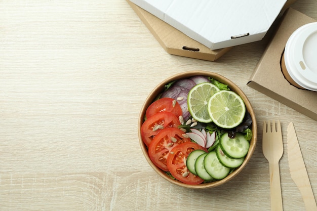 Concetto di consegna cibo con insalata di verdure su fondo in legno