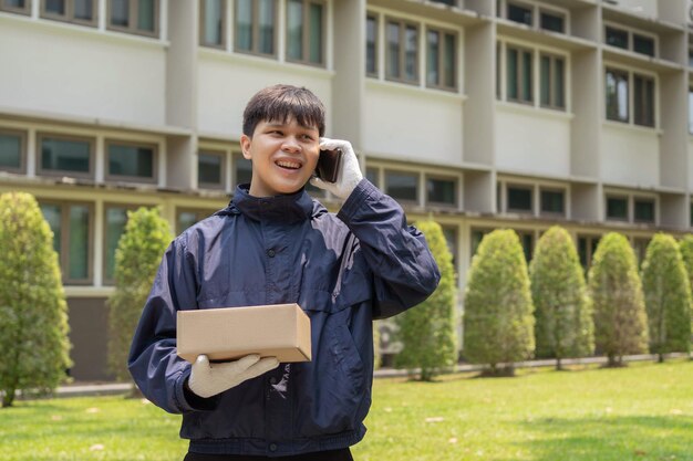 Concetto di consegna dei pacchi il postino in piedi di fronte all'edificio e chiamando il suo cliente