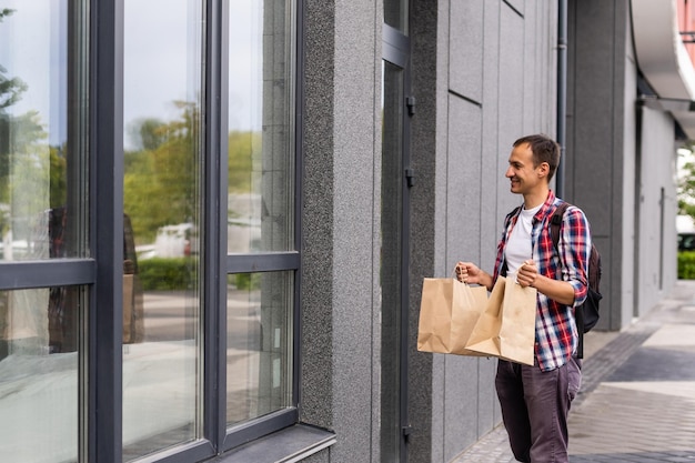 concetto di consegna, posta e persone - uomo felice che consegna cibo in un sacchetto di carta usa e getta a casa del cliente