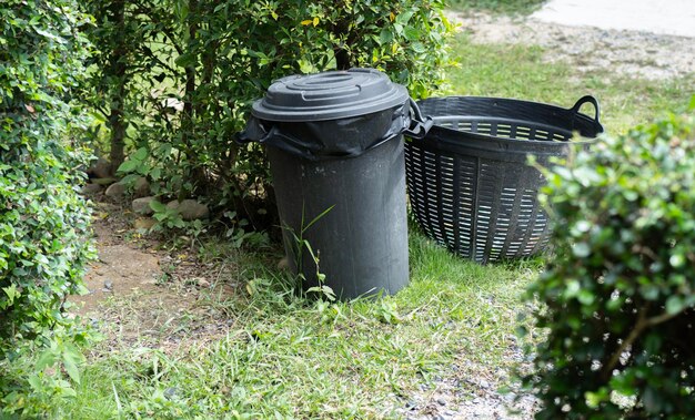 Concetto di conservazione dell'ambiente Contenitori di riciclaggio in plastica nera collocati nel giardino per la pulizia