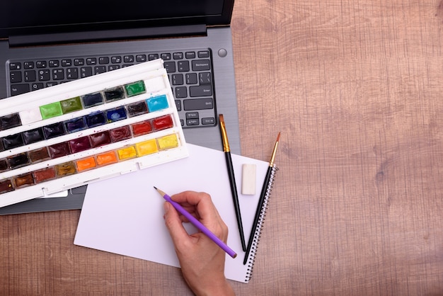 Concetto di copertina del corso di disegno online con foglio per laptop di colori di carta e pennelli su de...