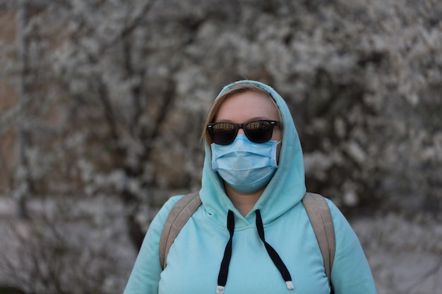 Concetto di coronavirus La ragazza che indossa una maschera protettiva dalla malattia e guanti protettivi è per strada