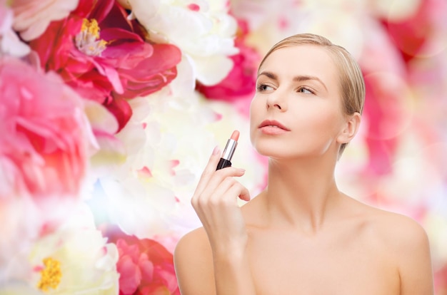 concetto di cosmetici, salute e bellezza - bella donna con rossetto rosa