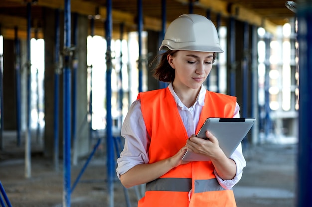 Concetto di costruzione di ingegnere o architetto che lavora al cantiere. Una donna con un tablet in un cantiere edile. Ufficio di architettura.