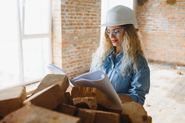 Concetto di costruzione. Generatore abbastanza femminile in tuta e casco lavorando sul cantiere.