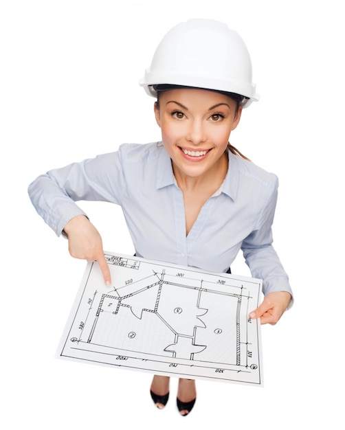 concetto di costruzione, sviluppo, costruzione e architettura - donna d'affari sorridente in casco bianco che punta il dito al progetto