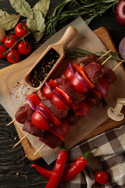 Concetto di cucina barbecue con shish kebab crudo e ingredienti su legno