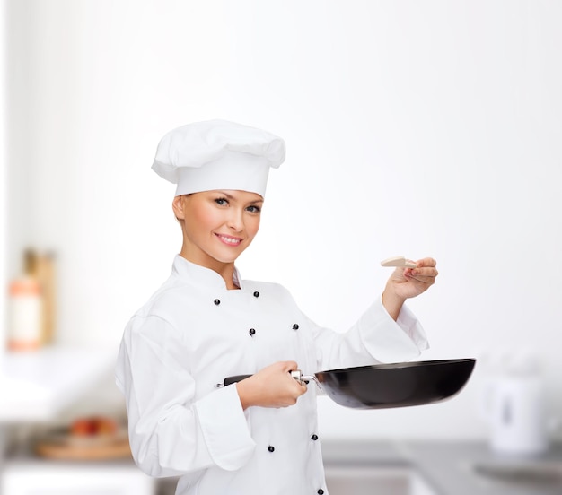 concetto di cucina e cibo - chef, cuoca o fornaio sorridente con padella e cucchiaio da degustazione