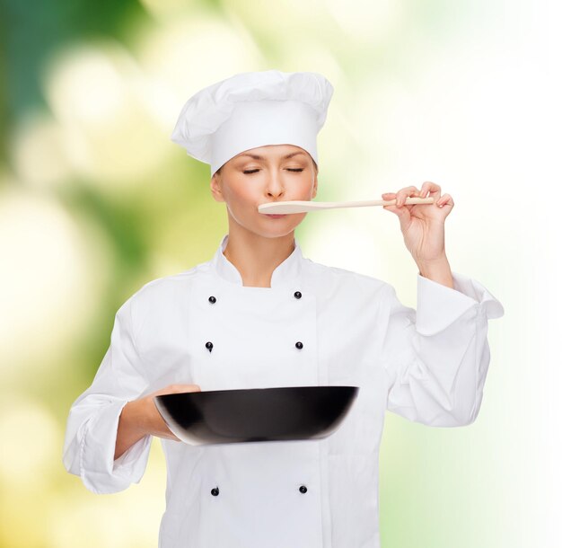 concetto di cucina e cibo - chef, cuoca o fornaio sorridente con padella e cucchiaio da degustazione