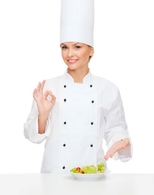 concetto di cucina e cibo - chef femminile sorridente con insalata sul piatto e segno ok