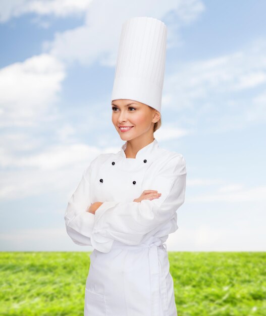 concetto di cucina e cibo - chef femminile sorridente con le braccia incrociate